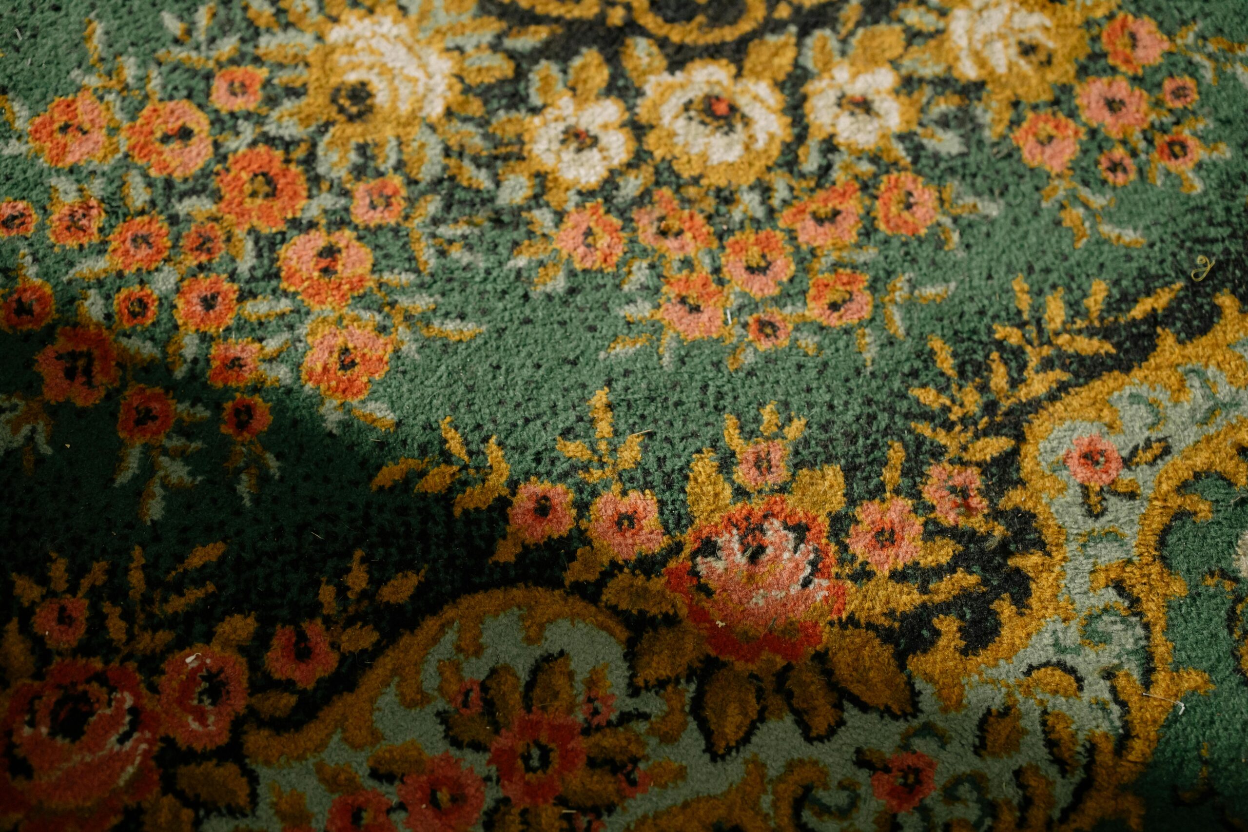 Close-up of a vintage floral patterned carpet with intricate textures and warm colors.